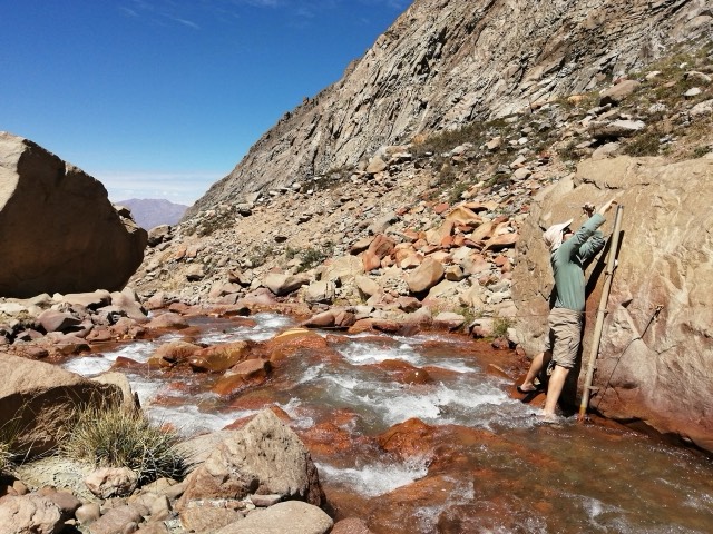 Profesional midiendo en un cauce de aguas rojizas