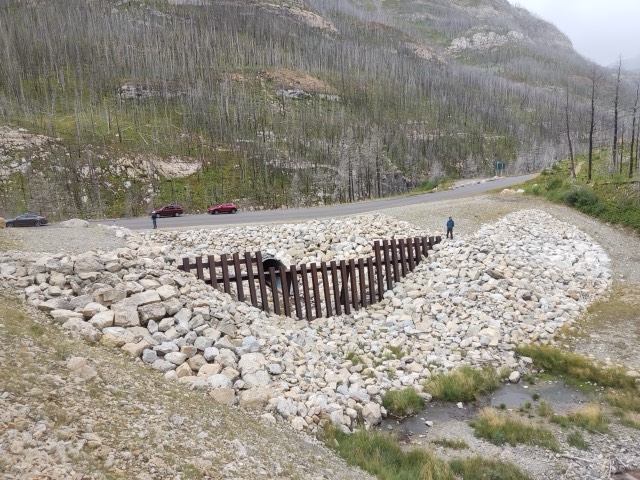 Obra de paso con rejilla y enrocado junto a un camino